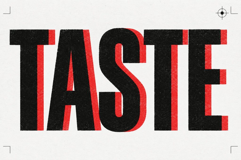 Perkataan TASTE dicetak besar dalam dakwat hitam bertindan merah atas kertas putih, kesan cetak tersasar sikit.